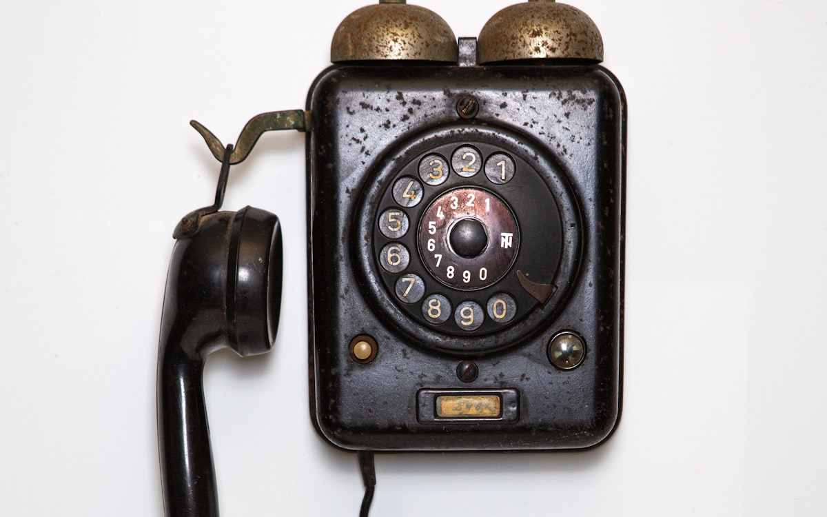 Telefone antigo de disco sobre fundo claro — o fim da URA e do menu de digite 1 frente à IA